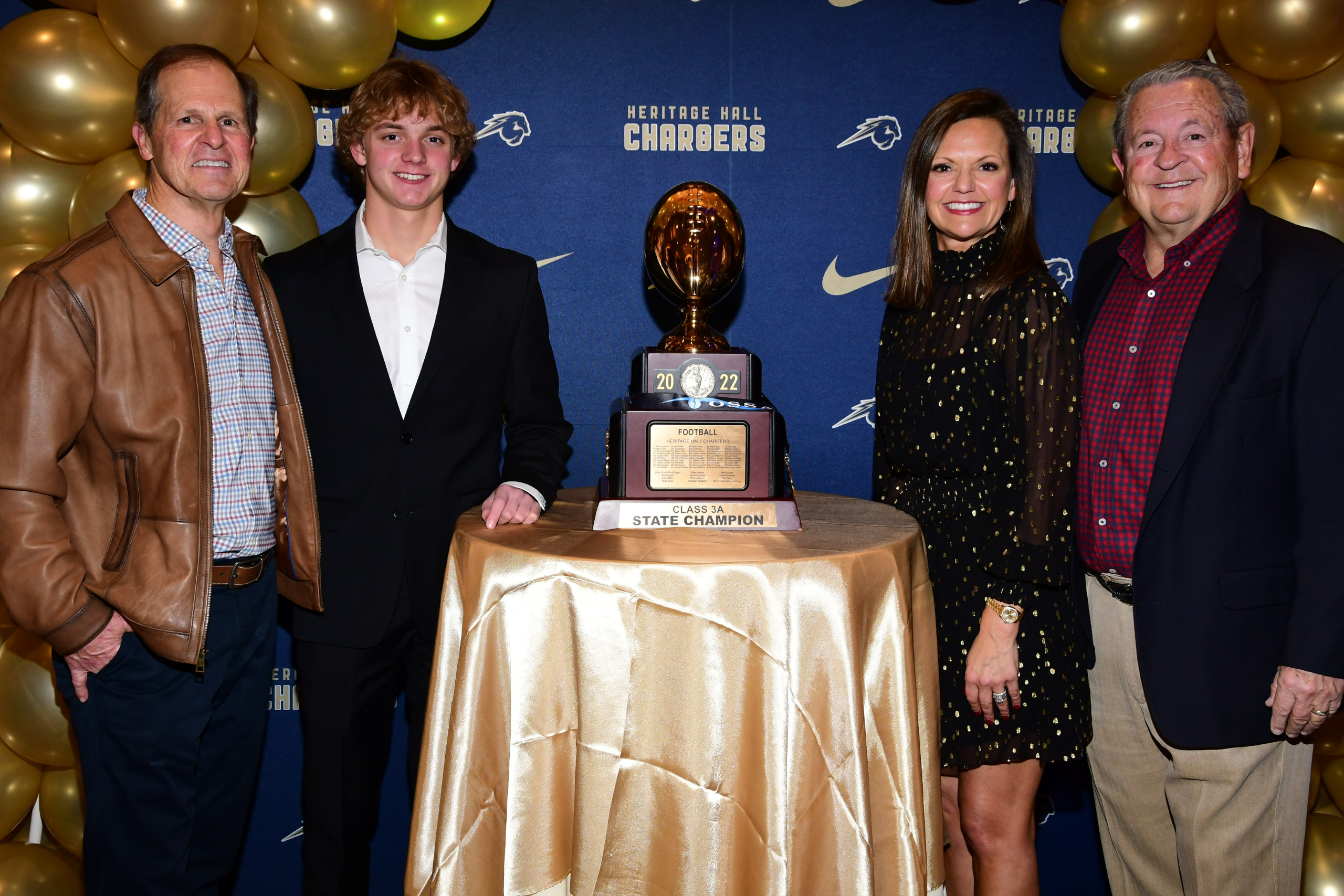 group of four people posing with a football trophy at an awards banquet